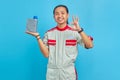 Portrait of cheerful handsome man wearing mechanic uniform showing engine oil plastic bottle in palm and showing gesturing okay