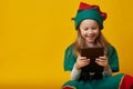 Portrait of a cheerful happy European little girl in elf costume laughing holding tablet Royalty Free Stock Photo