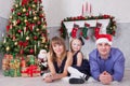 Portrait of cheerful happy family of three people lying on the floor near Christmas tree with xmas gifts. A fireplace with christm Royalty Free Stock Photo