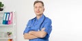 Portrait of cheerful happy male doctor in hospital with crossed hands. Surgeon with stethoscope on white background. Medical