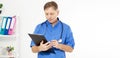 Portrait of cheerful happy male doctor in hospital takes notes. Surgeon with stethoscope on white background. Medical insurance