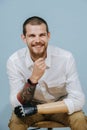 Portrait of a cheerful happy man with prosthetic bionic arm over blue background