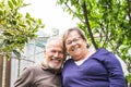 Portrait of cheerful happy senior aged couple smiling and having fun together in the garden looking at camera - retired lifestyle