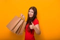 Portrait of a cheerful, happy, young woman with paper bags in hands standing on a yellow background. Shopping, discount day, black Royalty Free Stock Photo