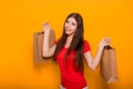 Portrait of a cheerful, happy, young woman with paper bags in hands standing on a yellow background. Shopping, discount day, black Royalty Free Stock Photo