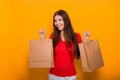 Portrait of a cheerful, happy, young woman with paper bags in hands standing on a yellow background. Shopping, discount day, black Royalty Free Stock Photo