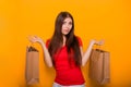 Portrait of a cheerful, happy, young woman with paper bags in hands standing on a yellow background. Shopping, discount day, black Royalty Free Stock Photo