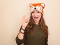 Portrait of a cheerful hipster girl in funny fox hat showing okay gesture