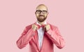 Portrait of cheerful imposing man who adjusting bow tie isolated on pink background.