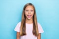 Portrait of cheerful impressed school girl with straight hairstyle wear pink t-shirt staring exited on blue