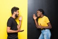 Portrait of cheerful indian man and african woman in basic clothing smiling and clenching fists for scream or happy people Royalty Free Stock Photo