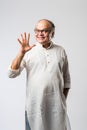 Portrait of cheerful Indian senior old man pointing or presenting or in hands folded pose Royalty Free Stock Photo