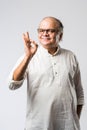 Portrait of cheerful Indian senior old man pointing or presenting or in hands folded pose Royalty Free Stock Photo