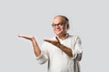 Portrait of cheerful Indian senior old man pointing or presenting or in hands folded pose Royalty Free Stock Photo