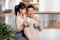 Portrait of cheerful korean spouses drinking tea at kitchen