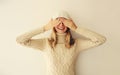 Portrait of cheerful laughing happy young woman covering her eyes with hands in warm soft knitted clothes, sweater and hat on Royalty Free Stock Photo