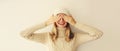 Portrait of cheerful laughing happy young woman covering her eyes with hands in warm soft knitted clothes, sweater and hat on Royalty Free Stock Photo