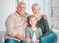 Portrait of a cheerful little girl and her grandparents sitting on the couch together during a visit at home. Loving Royalty Free Stock Photo