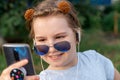 Portrait of a cheerful little girl in sunglasses taking a selfie outside in summer. Royalty Free Stock Photo