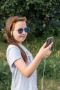 Portrait of a cheerful little girl in sunglasses taking a selfie outside in summer. Royalty Free Stock Photo