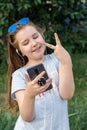 Portrait of a cheerful little girl in sunglasses taking a selfie outside in summer. Royalty Free Stock Photo