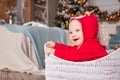 Portrait of a cheerful little kids in red reindeer costume of santa claus sitting in basket against the background of christmas Royalty Free Stock Photo