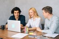 Portrait of cheerful male and female colleagues working on project together sitting at desk looking at laptop screen Royalty Free Stock Photo