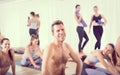 Portrait of a cheerful male hot yoga instructor relaxing after giving yoga class to large group of sporty attractive Royalty Free Stock Photo