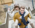 Portrait of cheerful man piggybacking woman on stairway Royalty Free Stock Photo