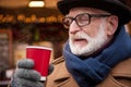 Positive senior male pensioner drinking mulled wine on street