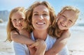 Portrait of a cheerful mature woman and little girls enjoying family time at the beach on vacation. Happy sisters Royalty Free Stock Photo