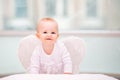 Portrait of cheerful mischievous baby with white angel wings