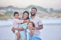 Portrait of a cheerful mixed race family laughing while standing together on the beach. Loving parents spending time Royalty Free Stock Photo