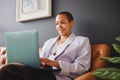 Portrait of cheerful multiracial LGBTQ mid adult woman using laptop on couch and smiling Royalty Free Stock Photo