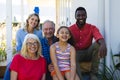 Portrait of cheerful multiracial multigeneration family sitting outside house in yard Royalty Free Stock Photo