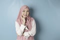 Portrait of a cheerful Muslim Asian woman standing and smiling at the camera,  on blue background Royalty Free Stock Photo