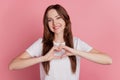 Portrait of cheerful nice pretty affectionate girl show heart symbol toothy smile on pink background