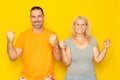 Portrait of cheerful people, caucasian man and woman in their 40s wearing basic clothes, smiling and clenching fists as Royalty Free Stock Photo