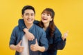 Portrait of cheerful people man and woman in basic clothing smiling and showing thumb up at camera isolated over yellow background Royalty Free Stock Photo