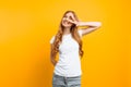 Portrait of a cheerful girl showing two fingers with winking eyes showing tongue against yellow background Royalty Free Stock Photo