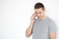 Portrait of a cheerful, positive, attractive guy with stubble in a gray T-shirt, talking on the phone on a gray background. Busine