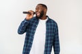 Portrait of cheerful positive chic handsome african man holding microphone singing song. Isolated on white background. Royalty Free Stock Photo