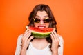 Portrait of cheerful positive cute nice cool youngster biting a wedge of watermelon wearing eyeglasses spectacles