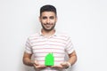 Portrait of cheerful positive glad optimistic young adult man in t-shirt have dream and holding paper small house, planning new Royalty Free Stock Photo