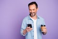 Portrait of cheerful positive man have free time relax after work use smartphone check social network hold mug with hot Royalty Free Stock Photo