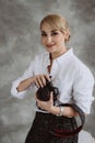 Portrait of a cheerful positive optimistic young woman photographer in the studio with a camera, on a gray background. Soft Royalty Free Stock Photo