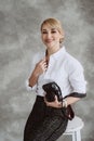 Portrait of a cheerful positive optimistic young woman photographer in the studio with a camera, on a gray background. Soft Royalty Free Stock Photo