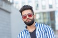 Portrait of cheerful positive stylish student guy in glasses with a mustache and beard outdoors. The concept of Royalty Free Stock Photo