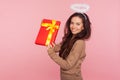 Portrait of cheerful pretty angelic young woman with halo holding big present and smiling to camera, satisfied with gift Royalty Free Stock Photo