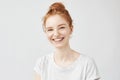 Portrait of cheerful redhead girl with hair bun laughing.